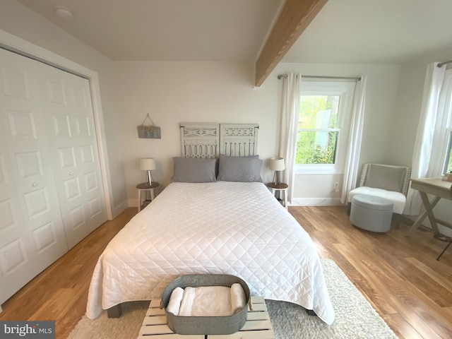 bedroom with light wood-style flooring, beamed ceiling, and baseboards