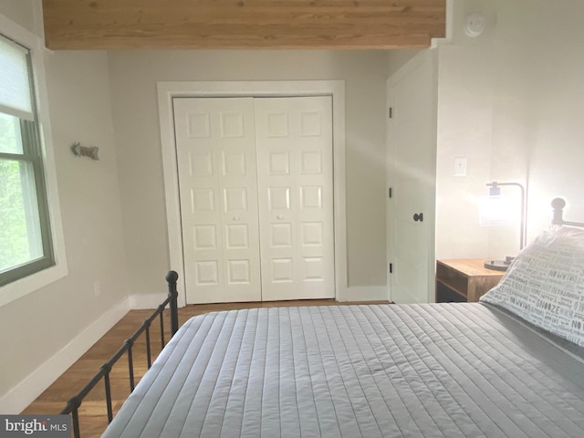 bedroom with wood finished floors, a closet, and baseboards