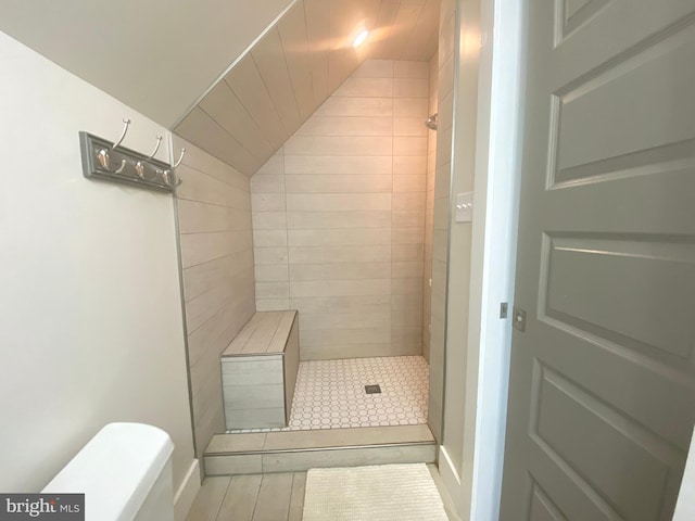 bathroom with a stall shower, lofted ceiling, and toilet