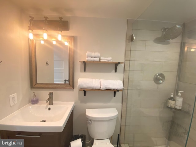 bathroom featuring vanity, tiled shower, and toilet