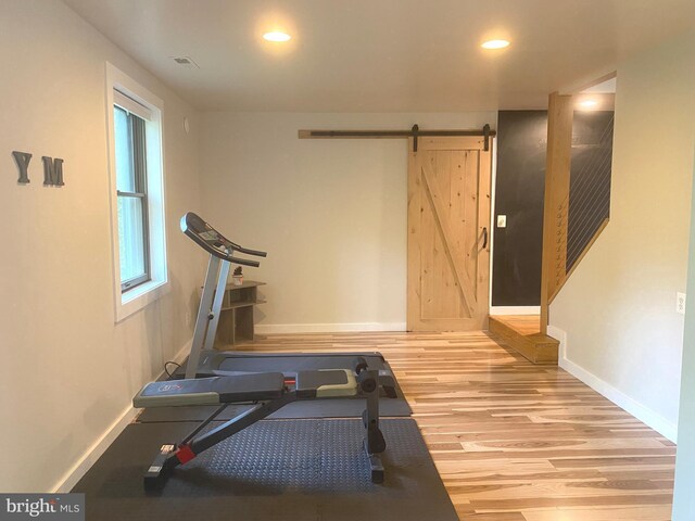 exercise area with a barn door, wood finished floors, baseboards, and recessed lighting