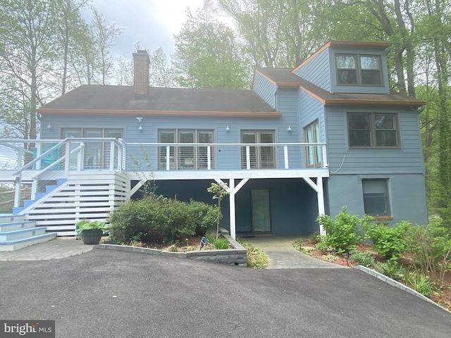rear view of house featuring stairway and a chimney