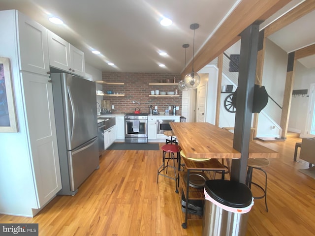 kitchen featuring stainless steel appliances, open shelves, light wood-style floors, pendant lighting, and white cabinets
