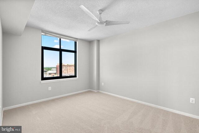 carpeted spare room with a textured ceiling, baseboards, and a ceiling fan