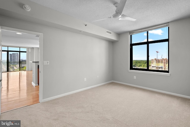 empty room featuring a smoke detector, carpet flooring, ceiling fan, a textured ceiling, and baseboards