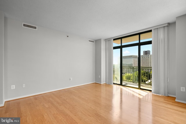spare room featuring floor to ceiling windows, wood finished floors, and baseboards