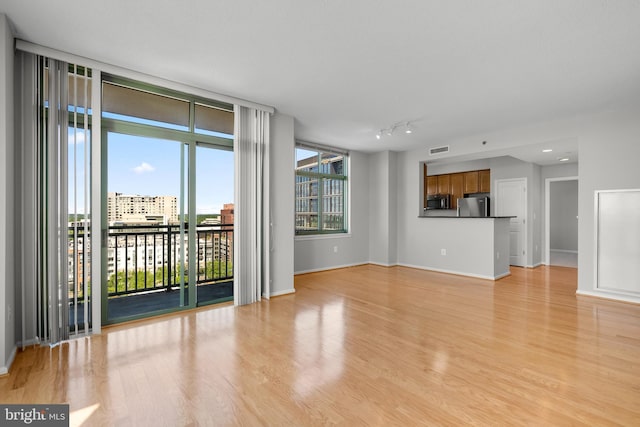 unfurnished living room featuring light wood finished floors and baseboards