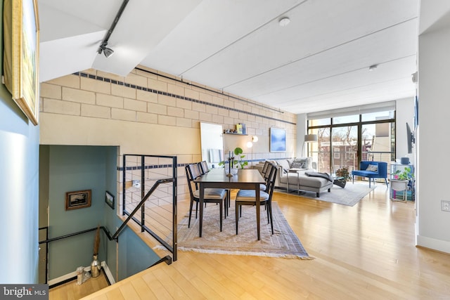 dining area with wood finished floors, track lighting, and floor to ceiling windows