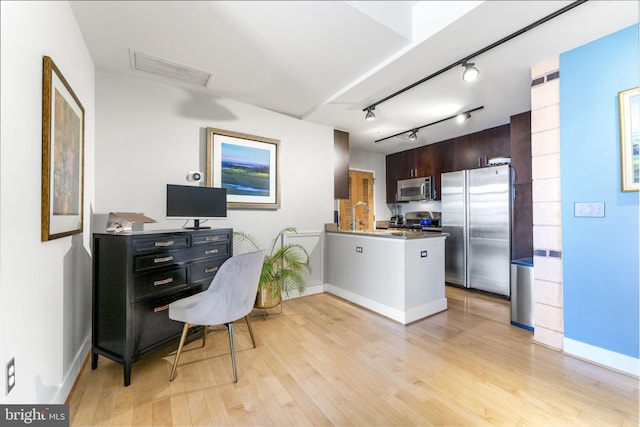office area featuring a sink, light wood-type flooring, baseboards, and rail lighting