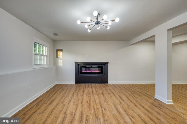 9815 Winands Rd, Randallstown, MD 21133 - unfurnished living room with wood finished floors, a chandelier, a glass covered fireplace, and baseboards