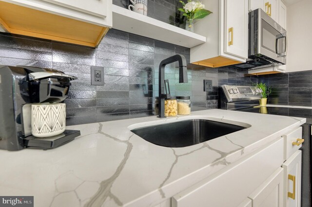 9815 Winands Rd, Randallstown, MD 21133 - kitchen with stainless steel appliances, a sink, backsplash, white cabinetry, and light stone counters
