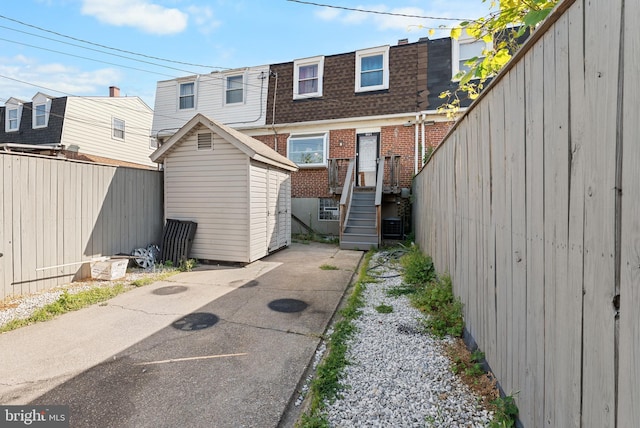 8031 Stratman Rd, Baltimore, MD 21222 - rear view of house featuring a storage shed, brick siding, roof with shingles, mansard roof, and an outbuilding