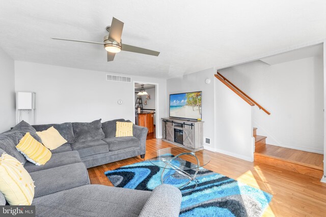 8031 Stratman Rd, Baltimore, MD 21222 - living room featuring stairs, light wood-style flooring, a ceiling fan, and baseboards