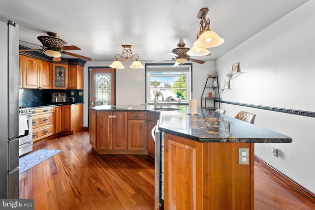8031 Stratman Rd, Baltimore, MD 21222 - kitchen with a ceiling fan, gas range, brown cabinets, a sink, and wood finished floors