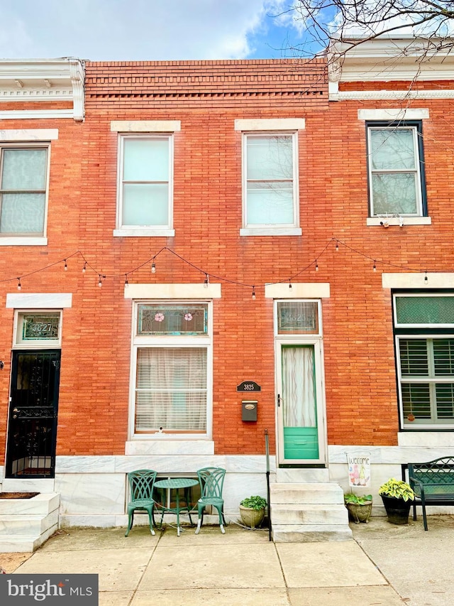 view of property with entry steps, brick siding, and a patio area