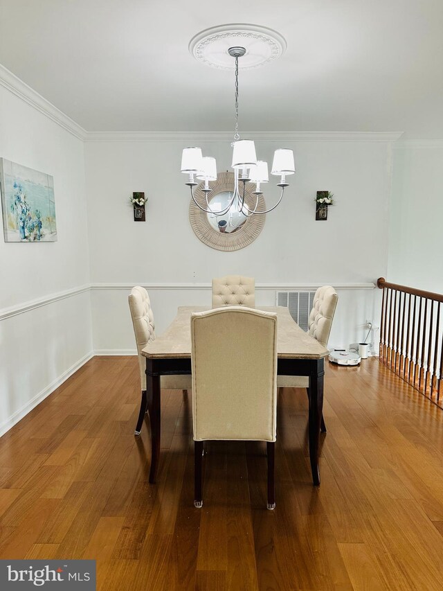 dining room with a chandelier, crown molding, and wood finished floors