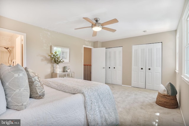 9807 Spillway Ct, Burke, VA 22015 - bedroom with light carpet, two closets, baseboards, a ceiling fan, and multiple windows