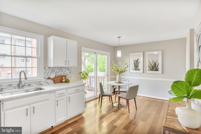 9807 Spillway Ct, Burke, VA 22015 - kitchen featuring a sink, backsplash, white cabinets, light wood-type flooring, and light countertops