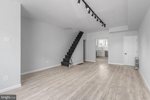1906 Durfor St, Philadelphia, PA 19145 - unfurnished living room featuring radiator heating unit, a sink, stairway, rail lighting, and light wood-type flooring