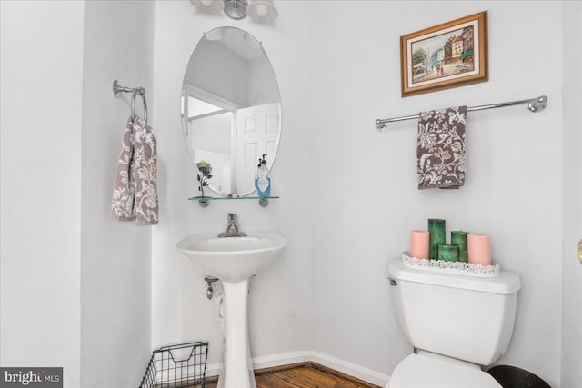 bathroom featuring toilet, baseboards, a sink, and wood finished floors