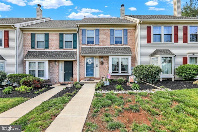 townhome / multi-family property featuring brick siding and a chimney