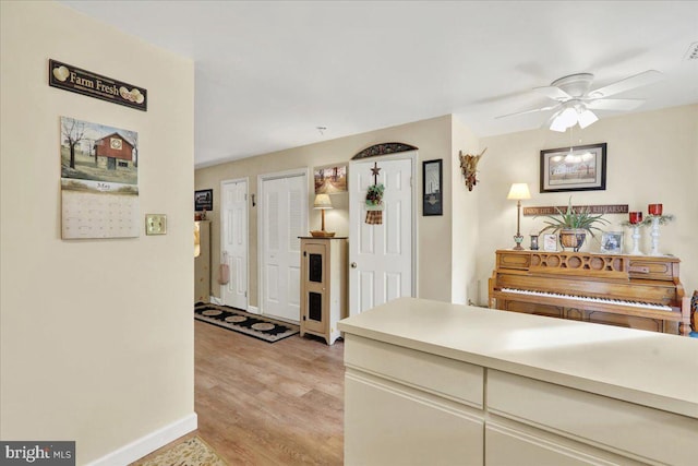 hallway featuring light wood finished floors and baseboards