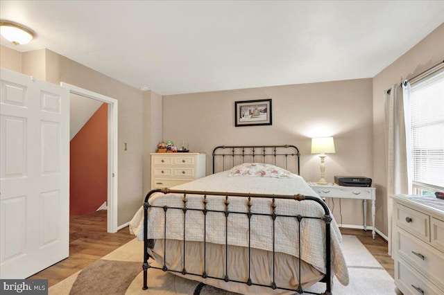 bedroom featuring multiple windows, light wood finished floors, and baseboards