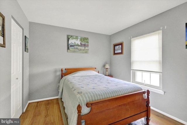 bedroom featuring baseboards, wood finished floors, and multiple windows