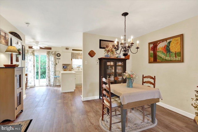dining space with a chandelier, wood finished floors, baseboards, and a ceiling fan