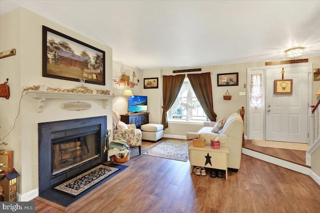 living area with wood finished floors, baseboards, and a fireplace with flush hearth