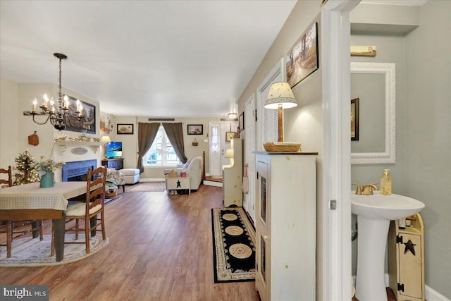 dining area with a chandelier, wood finished floors, a fireplace, and baseboards