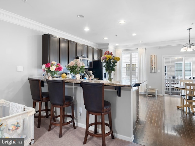1390 Parish Ave, Claymont, DE 19703 - kitchen with stainless steel microwave, a kitchen bar, crown molding, dark brown cabinets, and a peninsula