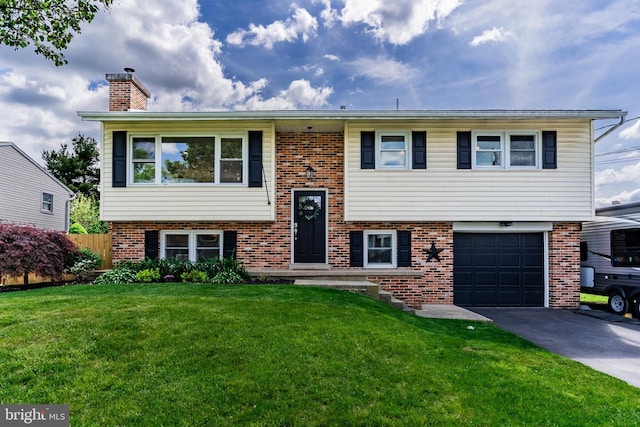 split foyer home with brick siding, driveway, a garage, and a front lawn
