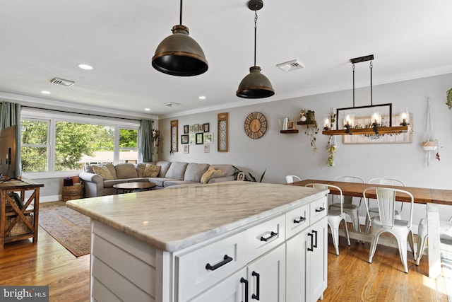 kitchen with ornamental molding, light wood-style floors, white cabinetry, a chandelier, and hanging light fixtures