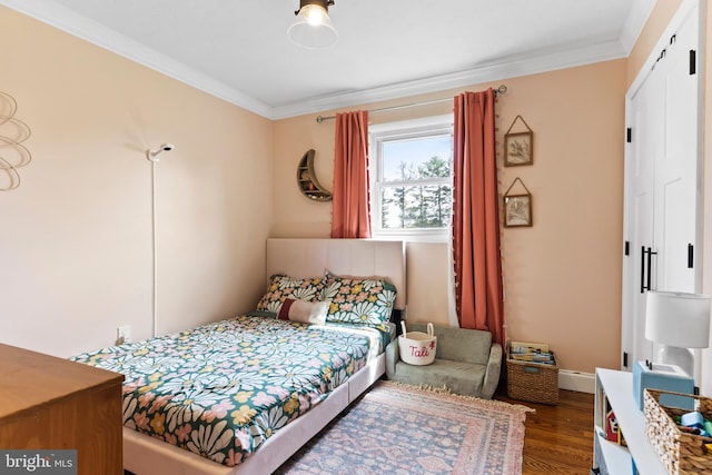 bedroom with ornamental molding, dark wood-style flooring, and baseboards