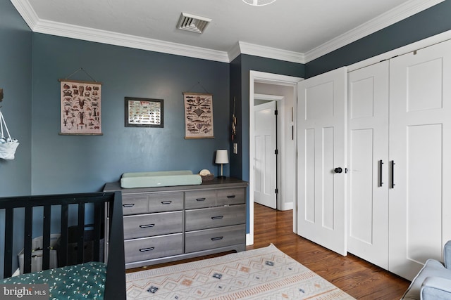 bedroom with dark wood-style floors, crown molding, and a closet