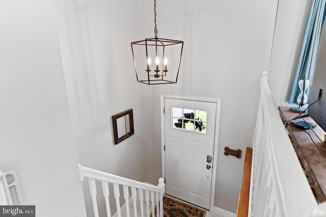 foyer entrance with a chandelier and baseboards