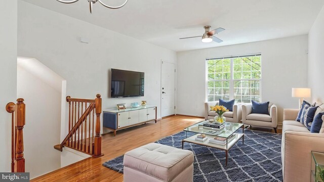 living area with light wood-style floors, a ceiling fan, and baseboards