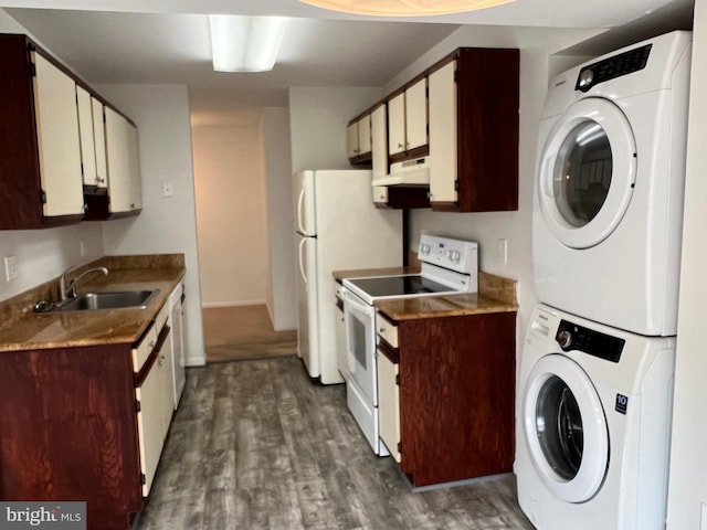 kitchen featuring white appliances, a sink, stacked washer and clothes dryer, under cabinet range hood, and dark wood finished floors