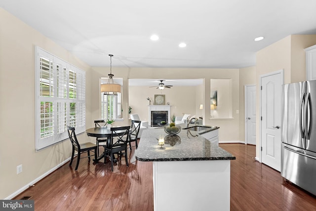 43127 Rocks Way, Leesburg, VA 20176 - kitchen with freestanding refrigerator, a sink, dark wood-style flooring, dark stone countertops, and a glass covered fireplace