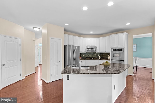 43127 Rocks Way, Leesburg, VA 20176 - kitchen with stainless steel appliances, a sink, wood finished floors, white cabinets, and tasteful backsplash