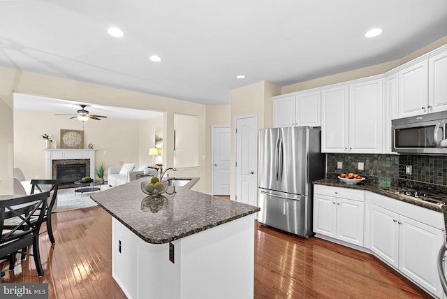 43127 Rocks Way, Leesburg, VA 20176 - kitchen with appliances with stainless steel finishes, ceiling fan, a glass covered fireplace, dark wood-style flooring, and white cabinetry