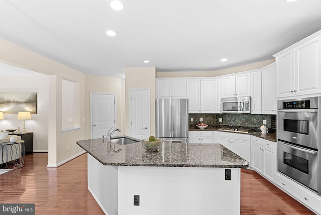 43127 Rocks Way, Leesburg, VA 20176 - kitchen with appliances with stainless steel finishes, a sink, a center island with sink, decorative backsplash, and dark stone counters