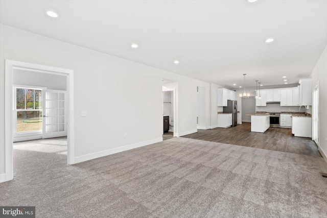 6741 Ginseng Ln, King George, VA 22485 - unfurnished living room featuring dark carpet, baseboards, recessed lighting, and a chandelier