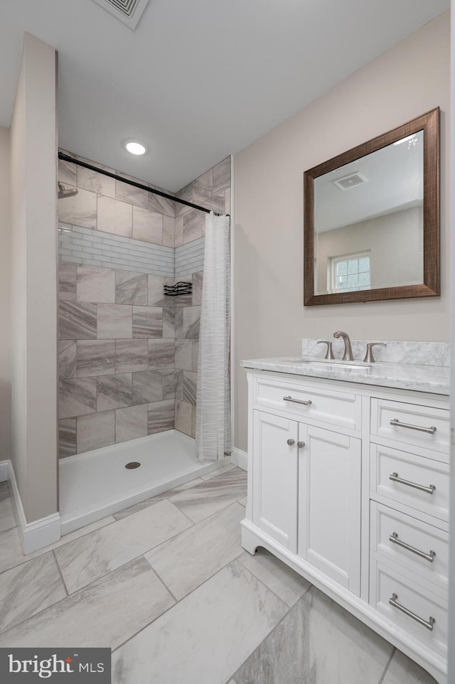 bathroom with marble finish floors, baseboards, a tile shower, vanity, and recessed lighting