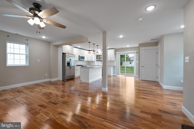 unfurnished living room with ceiling fan, baseboards, wood finished floors, and recessed lighting