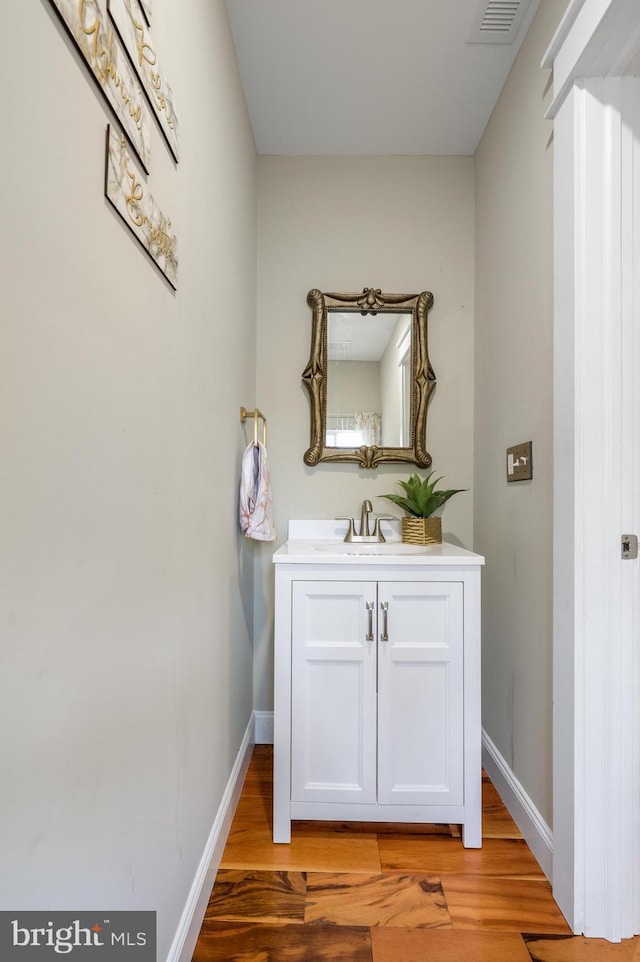 bathroom with wood finished floors, vanity, and baseboards