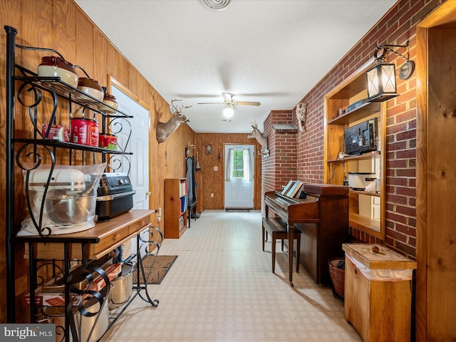 living area featuring brick wall, light flooring, a ceiling fan, and wood walls