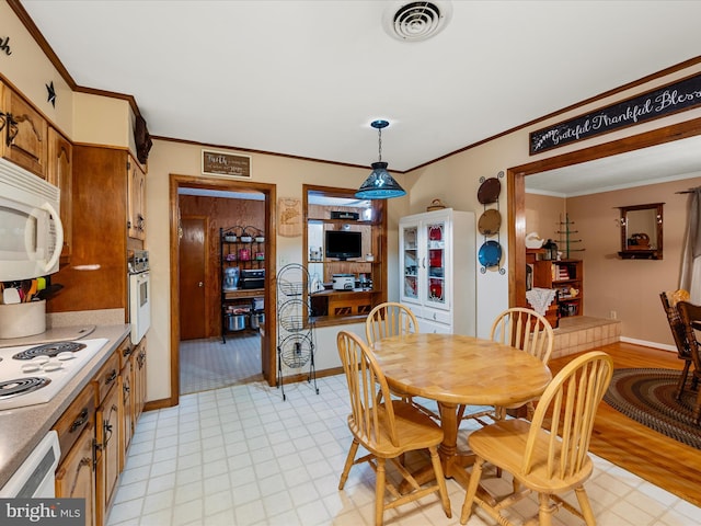 dining area featuring crown molding, baseboards, and light floors
