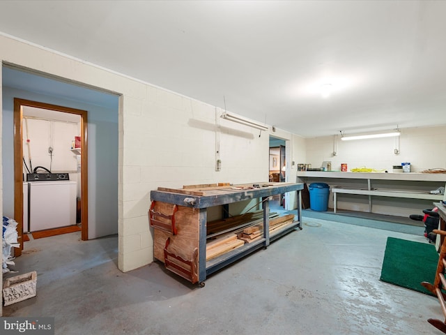 below grade area with washer / dryer, a workshop area, and concrete block wall